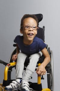 Julian wearing glassing in a wheelchair smiling